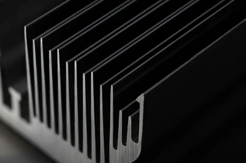 Nahaufnahme eines dunklen Aluminium-Kuehlkoerpers mit parallelen Rippen.