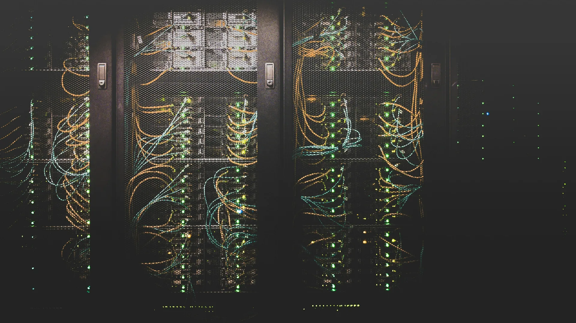 Offener Serverschrank mit sauber gebündelten Netzwerkkabeln in Orange und Türkis vor dunklem Hintergrund.